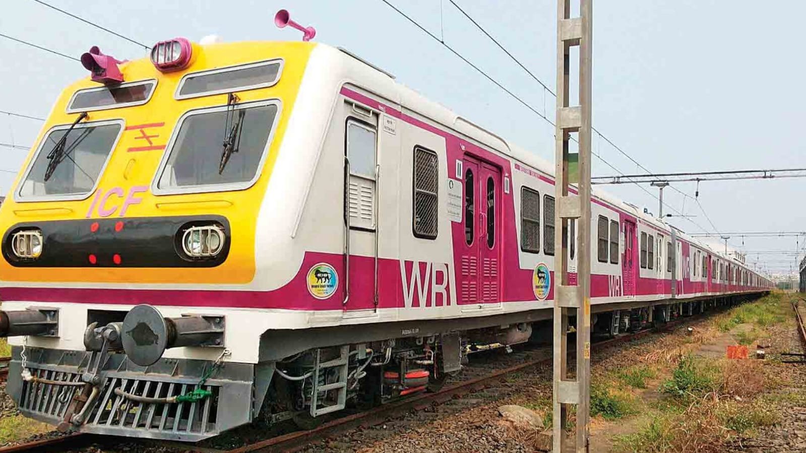 Indian Railways local passenger train standing on railway tracks at a station.