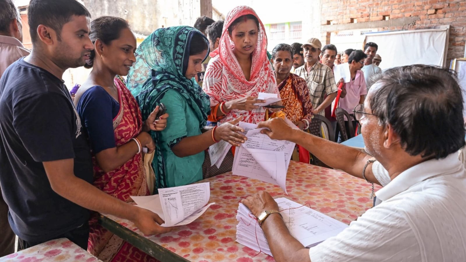 Women submitting documents to a government official at a public service centre.