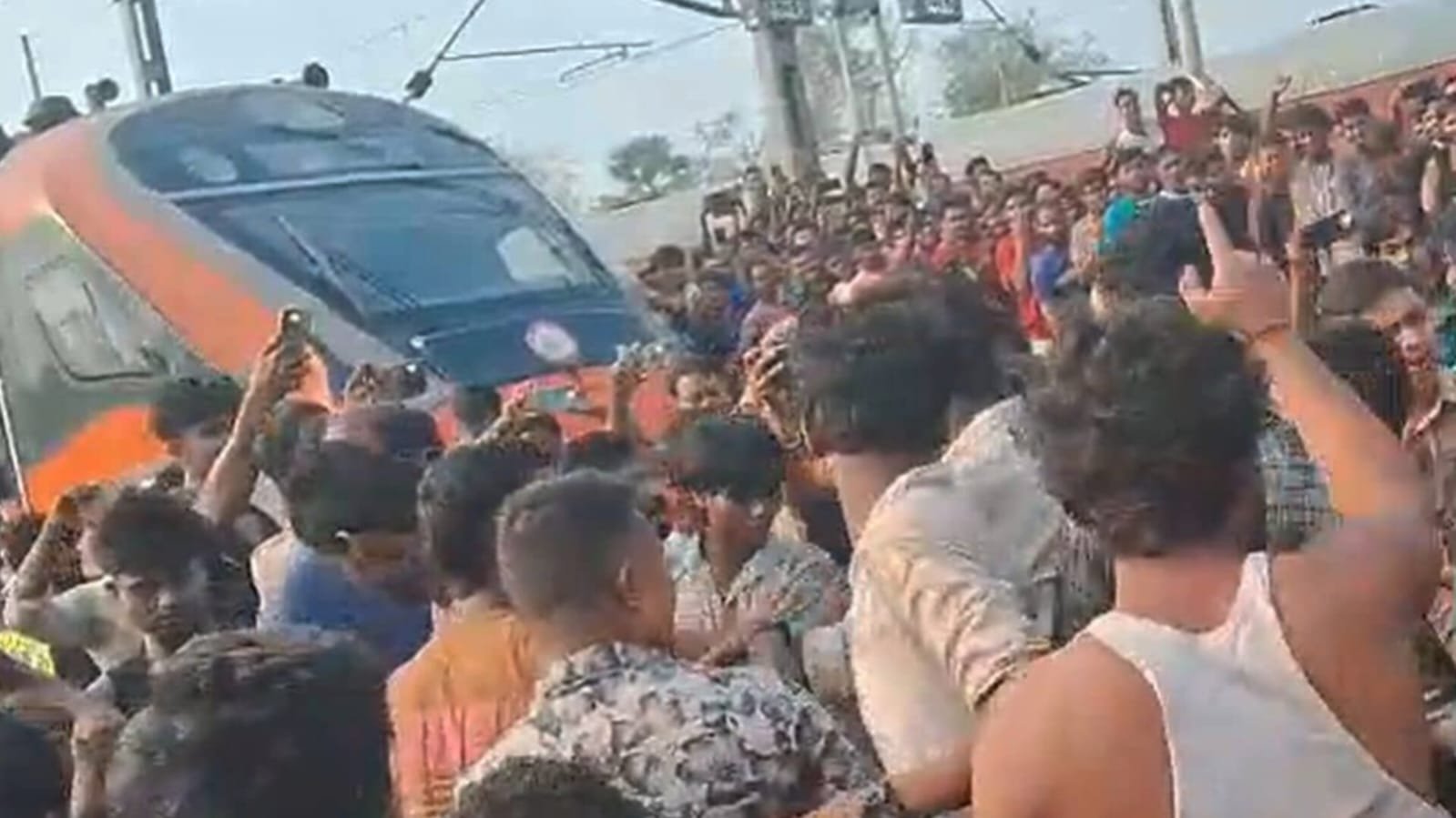 Passengers gather around a Vande Bharat Express train during a protest at Kamarkundu railway station in Hooghly, West Bengal, amid allegations of a prolonged train delay.