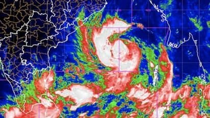 Satellite weather image showing a large cyclonic storm system over the Bay of Bengal near eastern India and Bangladesh coastline, with red, green and white cloud patterns indicating intense rainfall.