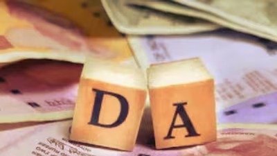 Two wooden blocks with the letters D and A on them, spelling DA, placed on top of scattered Indian currency notes.