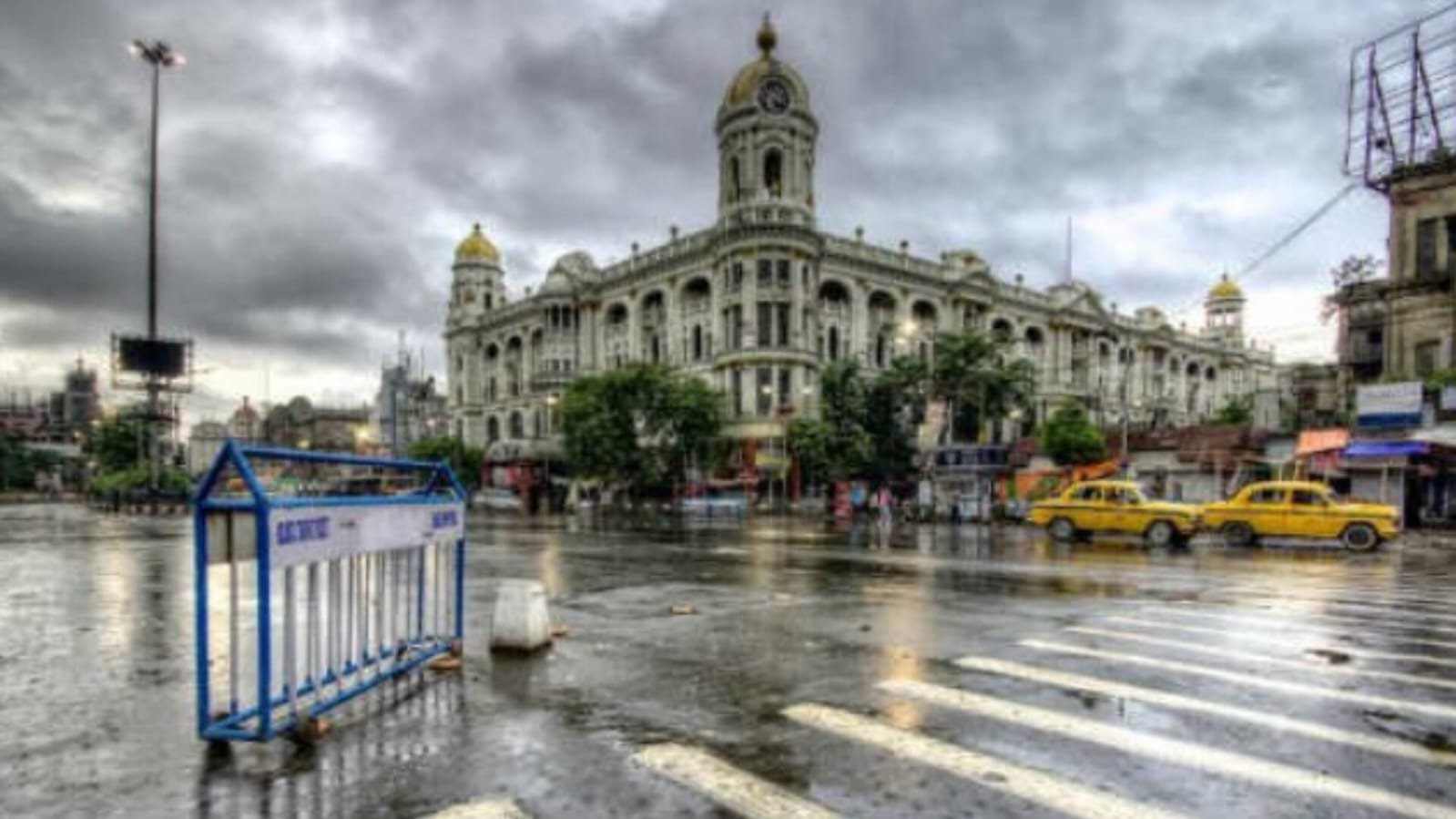 Rainy day in Kolkata - Esplanade crossing with wet road, cloudy sky and yellow taxis in front of Metropolitan Building