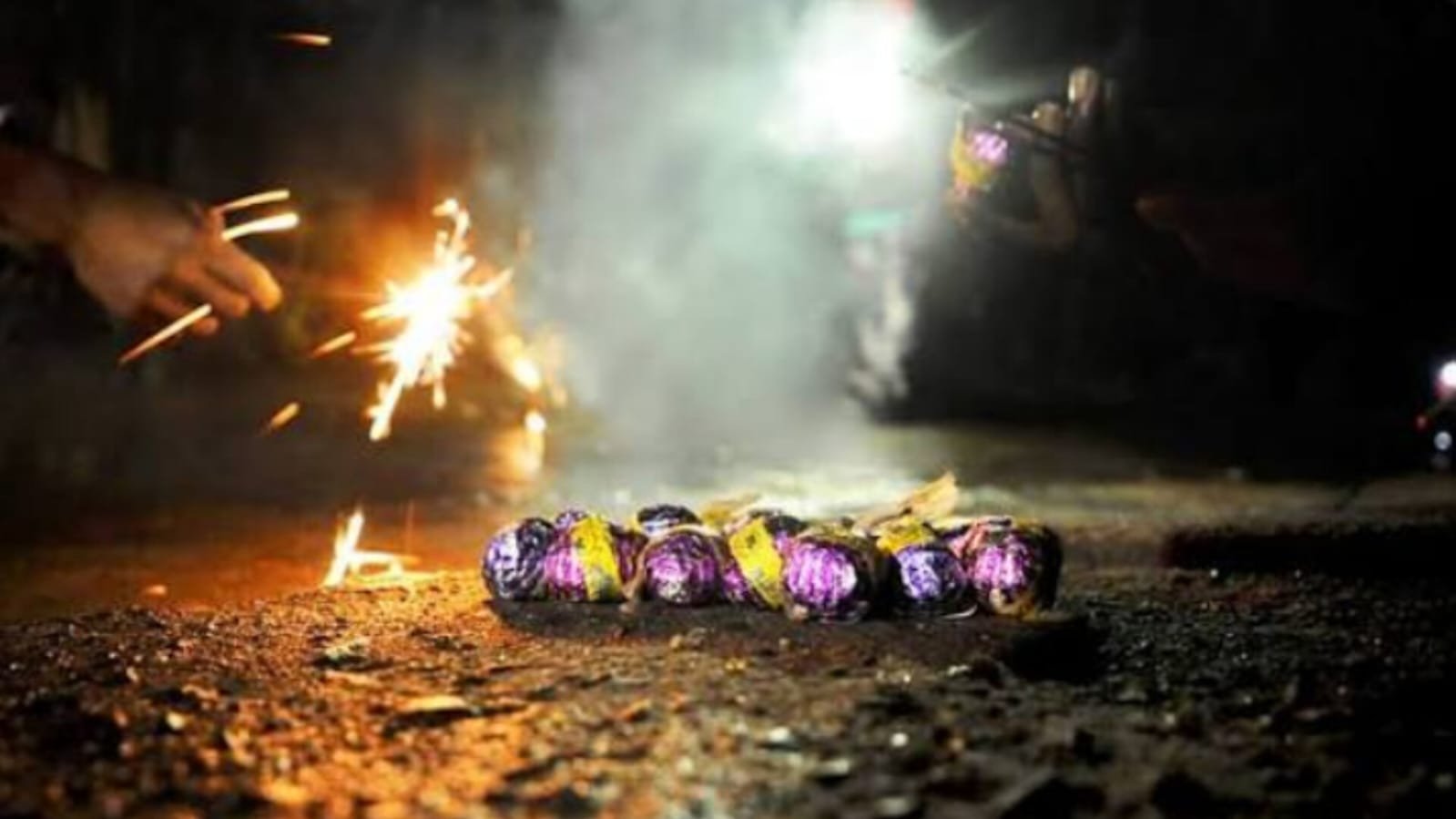 People bursting firecrackers on road at night - Diwali celebration with sparklers and flower pot crackers